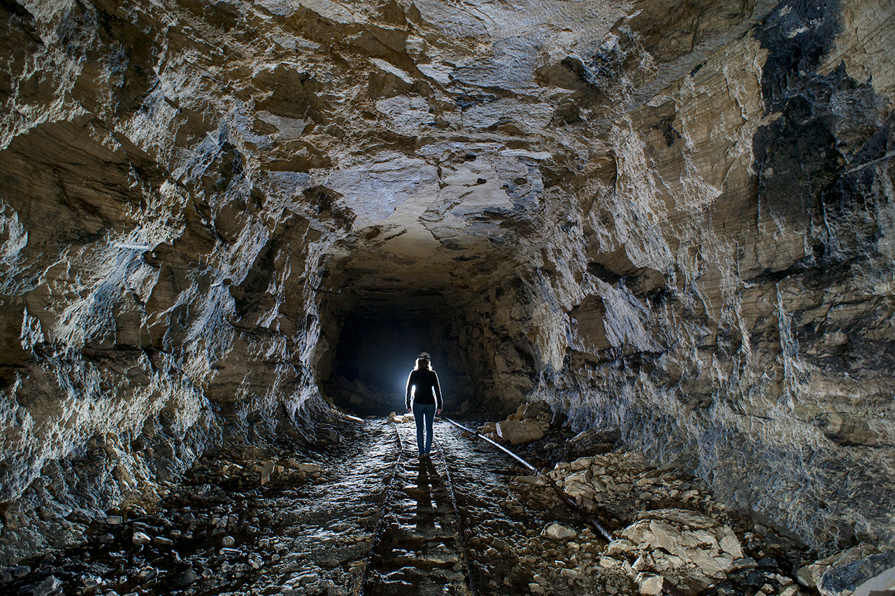 Portion de rails et silhouette dans une galerie.